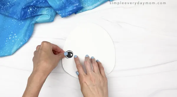 hand gluing eye to paper plate beluga whale craft