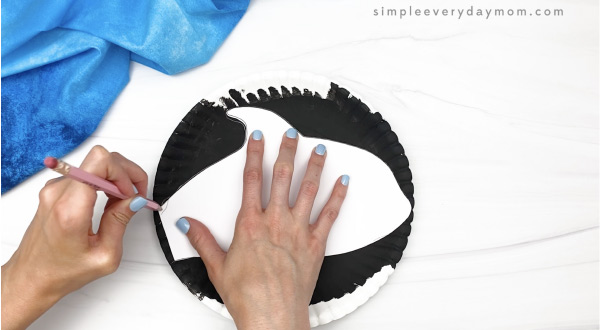 hand tracing killer whale body on paper plate