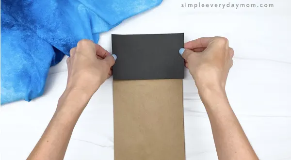 hand gluing black paper to brown paper bag