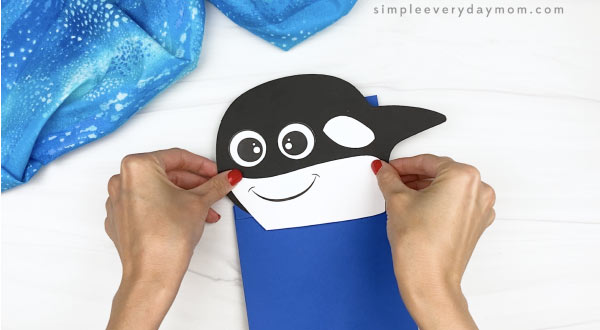 hand gluing head to killer whale paper bag craft