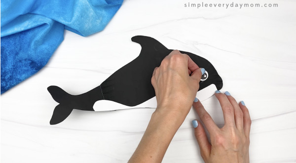 hand gluing eye to paper plate whale