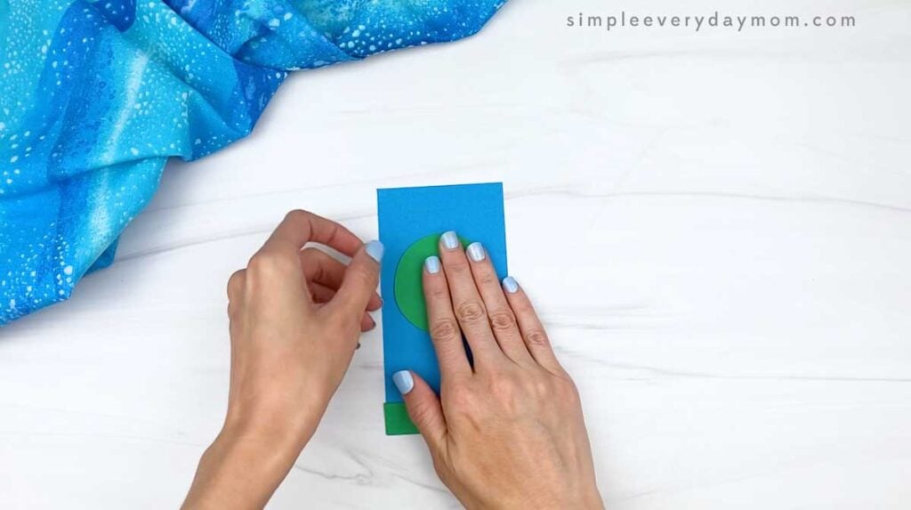 Hands placing a green circular frame onto the blue rocket body.