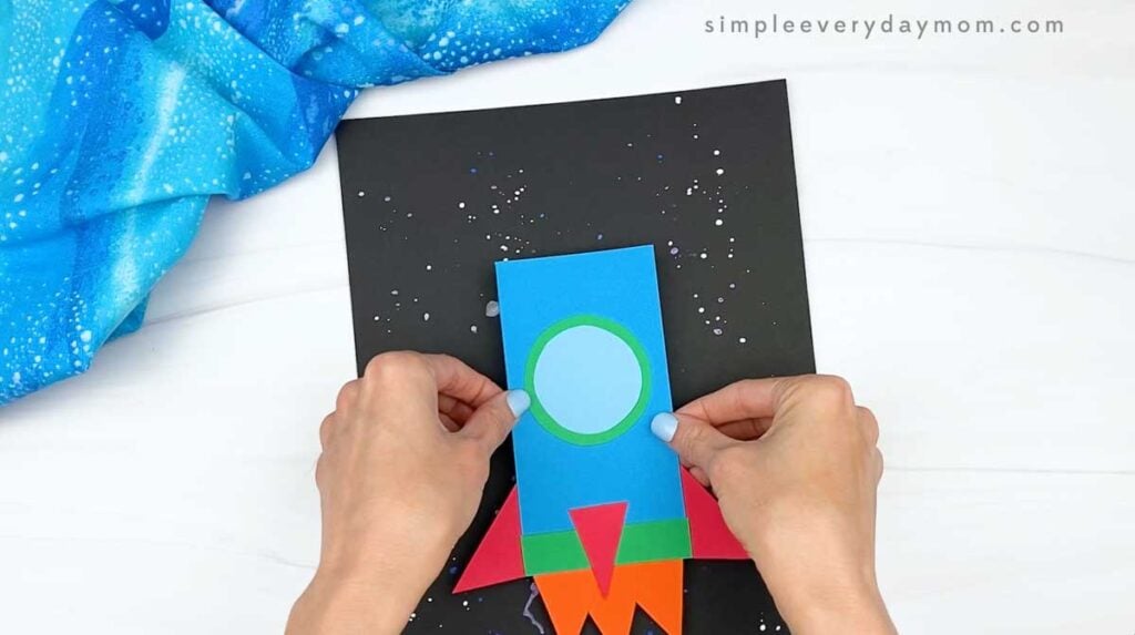 Hands positioning the completed rocket on a black, star-speckled background.
