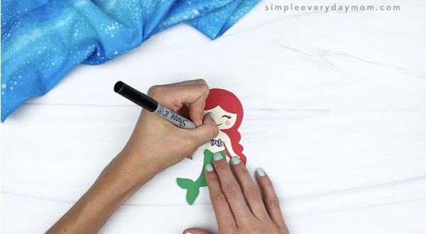 hand outlining seashell top on toilet paper roll mermaid