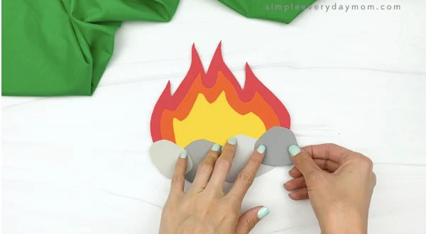 hand gluing rock to paper campfire craft
