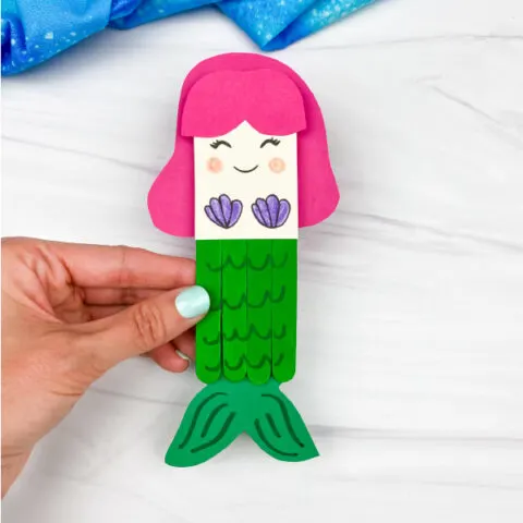 hand holding popsicle stick mermaid