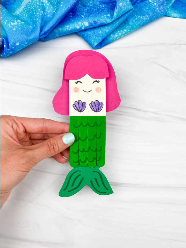 hand holding popsicle stick mermaid