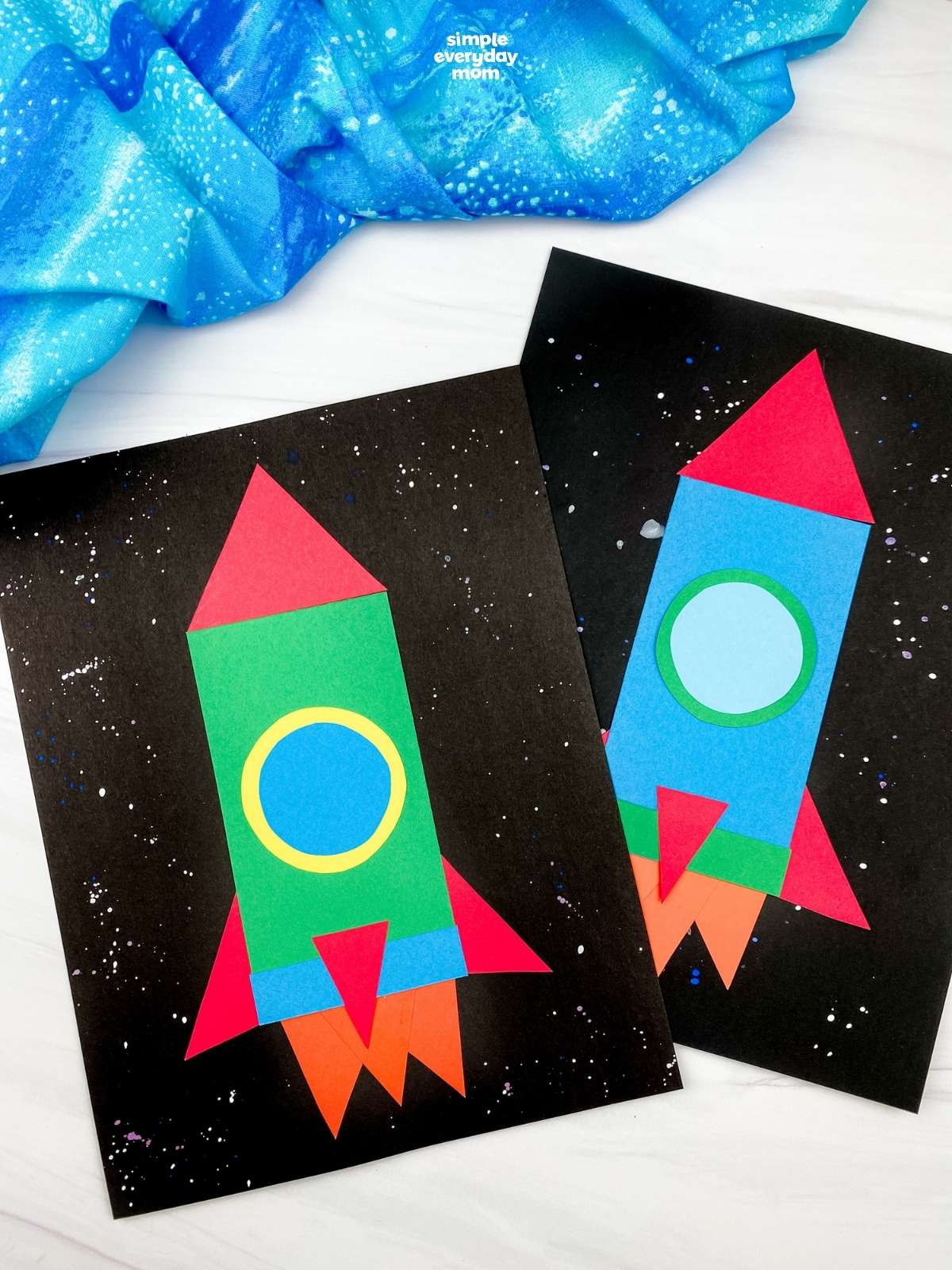 Two finished paper rocket crafts in green and blue displayed on black star-speckled backgrounds.