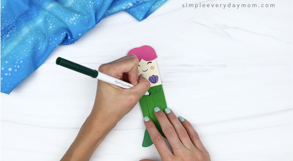 hand drawing scales onto popsicle stick mermaid craft