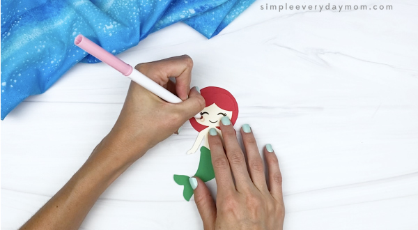 hand drawing cheeks onto toilet paper roll mermaid