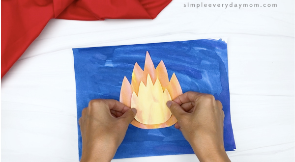 hand gluing campfire flame to art project