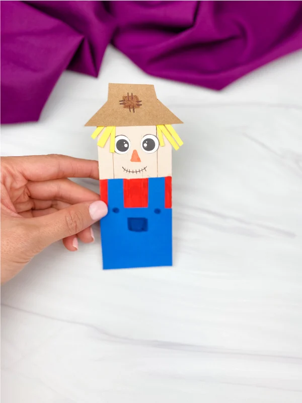 hand holding popsicle stick scarecrow craft