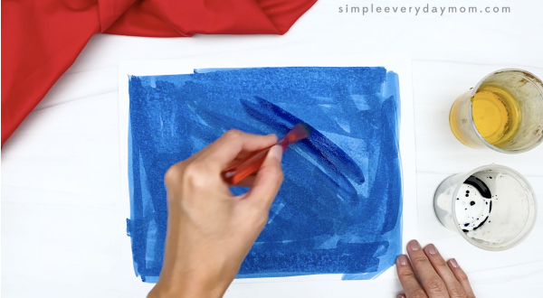hand painting white paper with blue watercolors