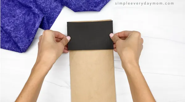 hand gluing black paper to brown paper bag