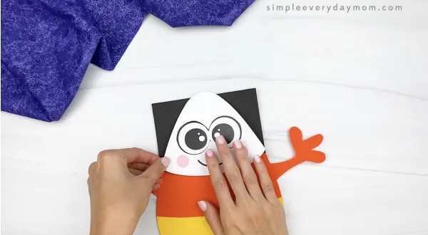 hand gluing head to candy corn puppet craft