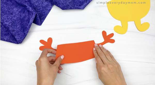 hand gluing arms to body of candy corn puppet craft