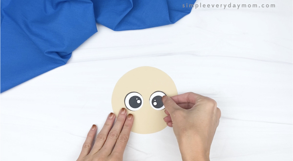 hand gluing eye to shape scarecrow craft