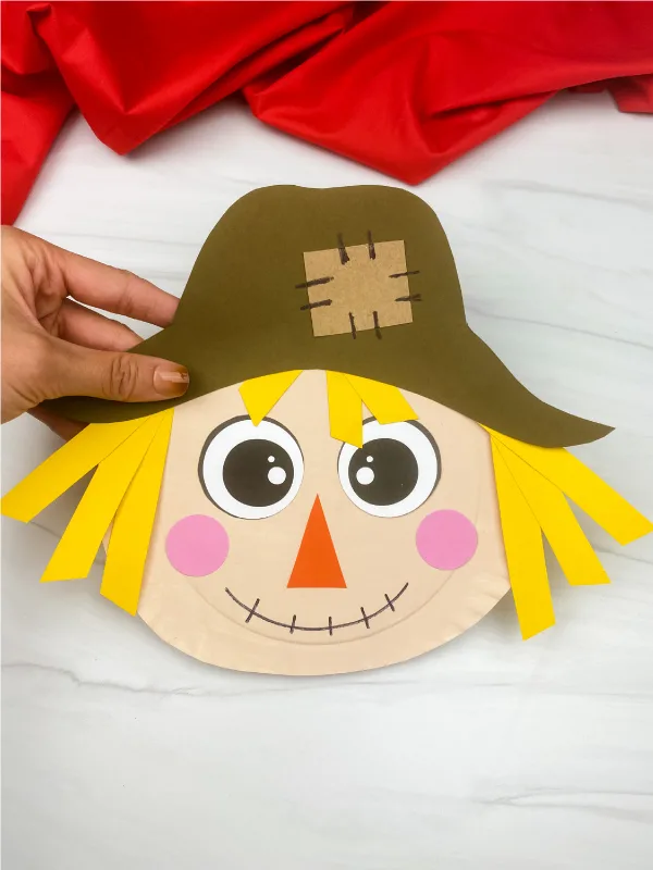 hand holding paper plate scarecrow craft