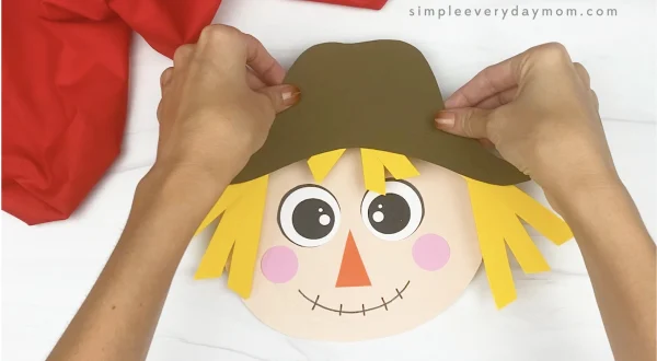 hand gluing hair to paper plate scarecrow craft