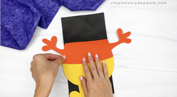 hand gluing middle body to candy corn puppet craft