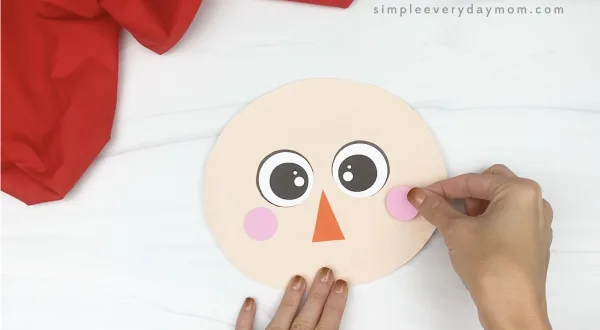 hand gluing cheeks to paper plate scarecrow craft