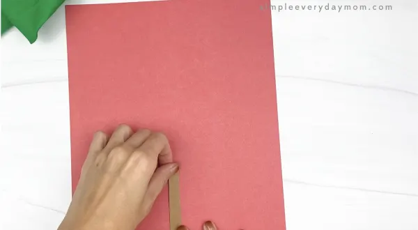 hand gluing brown rectangle to red paper