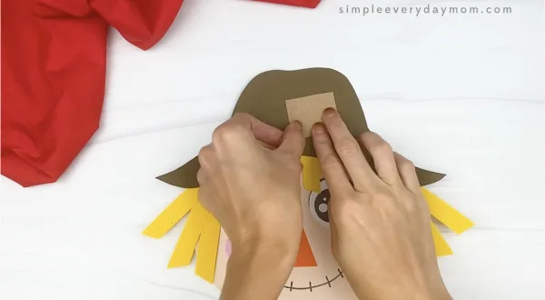 hand gluing patch to paper plate scarecrow craft