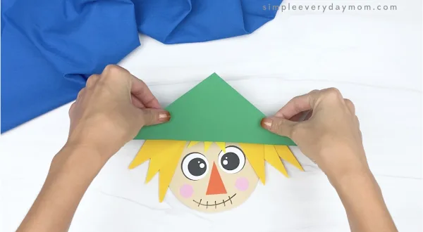 hand gluing hat to shape scarecrow craft