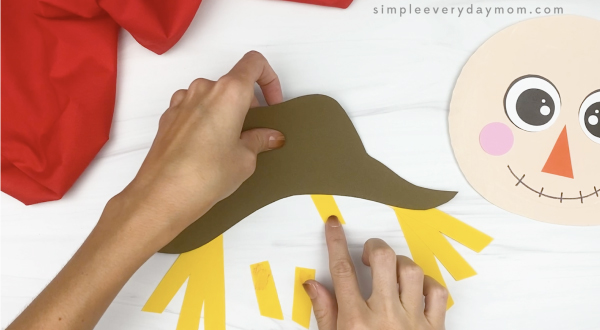 hand gluing bangs to paper plate scarecrow craft