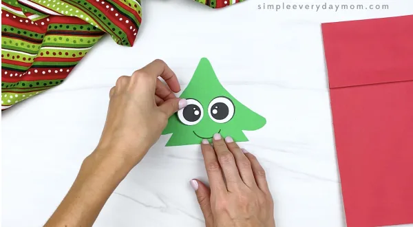 hand gluing eyes to paper bag Christmas tree craft