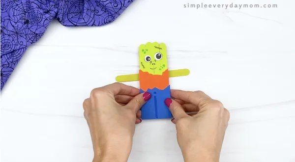 hand gluing arms to popsicle stick zombie