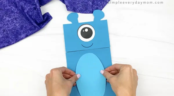 hand gluing belly to alien paper bag puppet craft