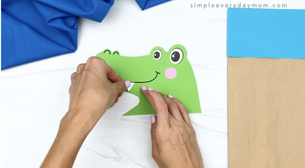 hand gluing teeth to paper bag alligator head