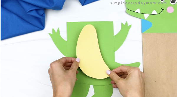 hand gluing belly to paper bag alligator craft