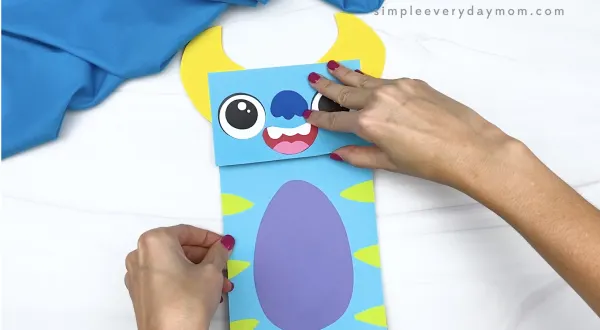 hand gluing body to monster paper bag craft