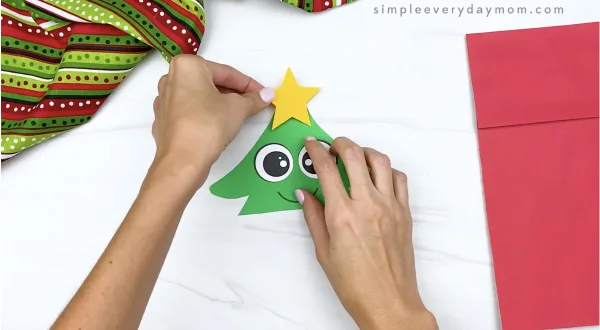 hand gluing star to paper bag Christmas tree craft
