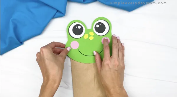 hand gluing head to paper bag frog craft