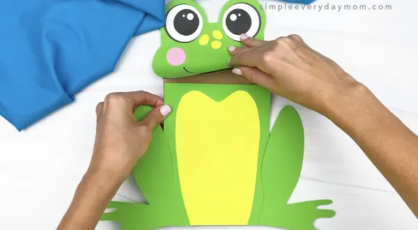 hand gluing body to paper bag frog craft