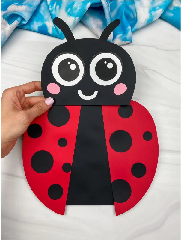 hand holding paper bag ladybug craft