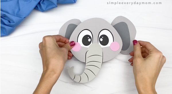 hand gluing ears to paper bag elephant craft