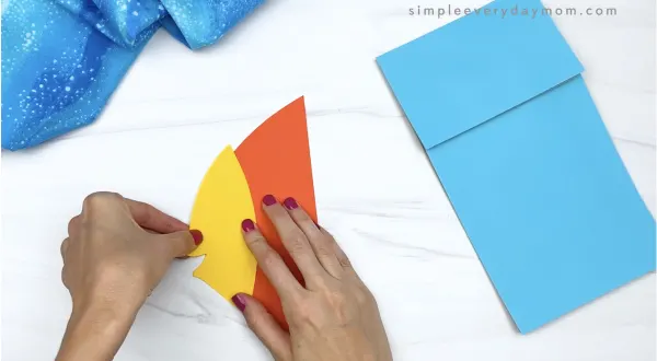 hand gluing face to paper bag fish craft
