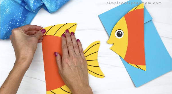 hand gluing dorsal fin to paper bag fish craft