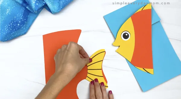 hand gluing tail fin to paper bag fish craft