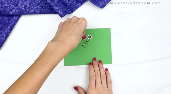 hand gluing eye to toilet paper roll zombie craft