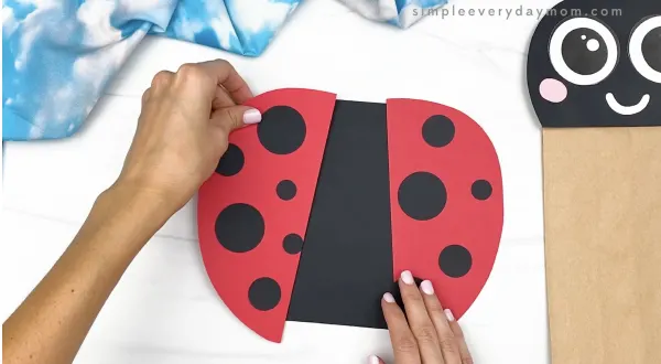 hand gluing wings to ladybug paper bag craft