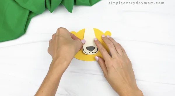hand gluing nose and mouth to paper bag lion craft
