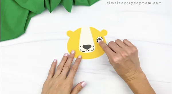 hand gluing eye to paper bag lion craft
