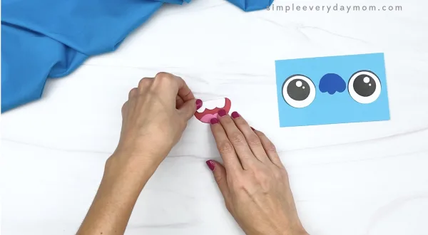 hand gluing teeth to paper bag monster mouth