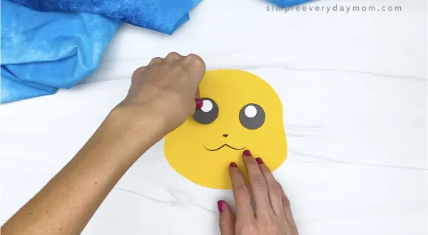 hand gluing eye to paper bag Pikachu craft