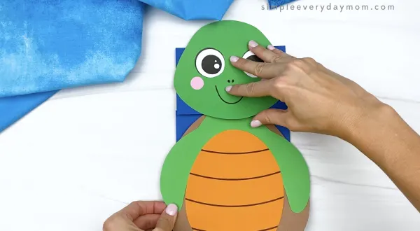hand gluing body to paper bag turtle craft